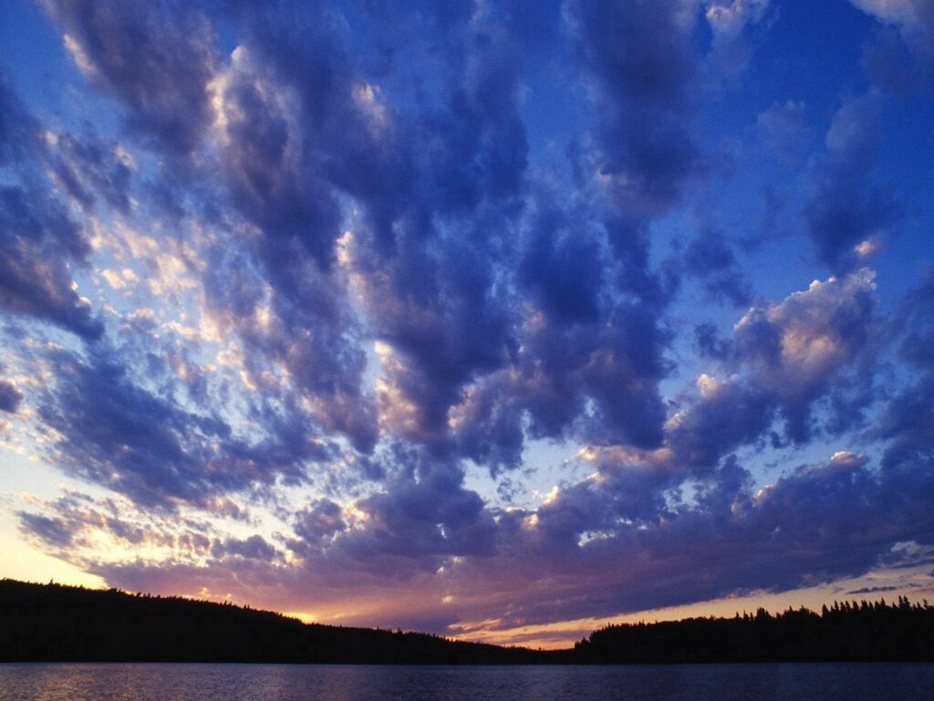Tranquil evening lake with dramatic clouds vibrant blue purple sky and silhouette trees wallpaper