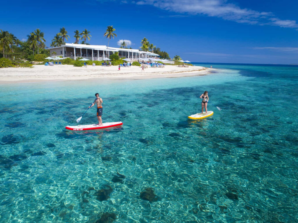 Tranquil Fiji Beach Scene: Paddleboarding in Turquoise Waters Wallpaper