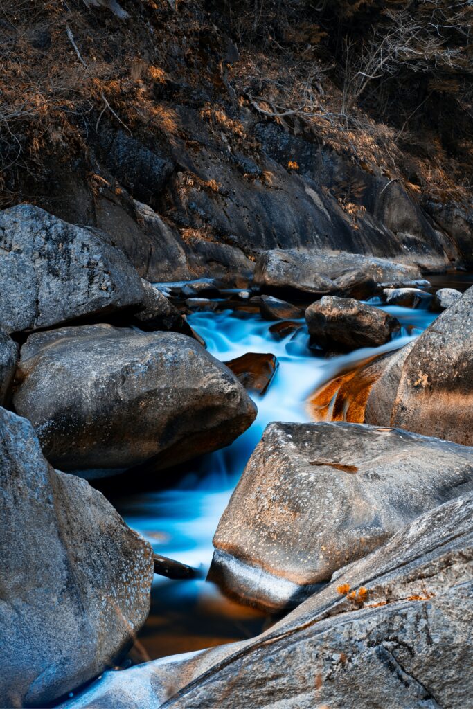 Serene wallpaper of smooth flowing water over weathered stones with earthy tones and blue highlights