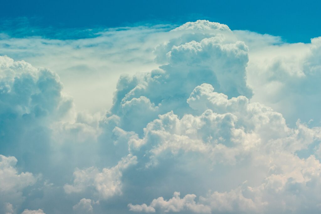 Fluffy porous clouds rise against vibrant blue sky creating tranquil airy wallpaper background