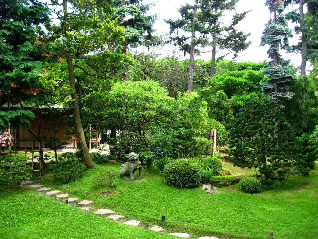 Serene garden wallpaper with winding stone path lush greenery dense trees and garden statue