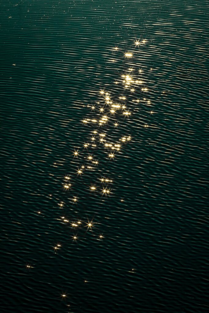 Glossy deep green water ripples with sparkling reflections creating a tranquil wallpaper background