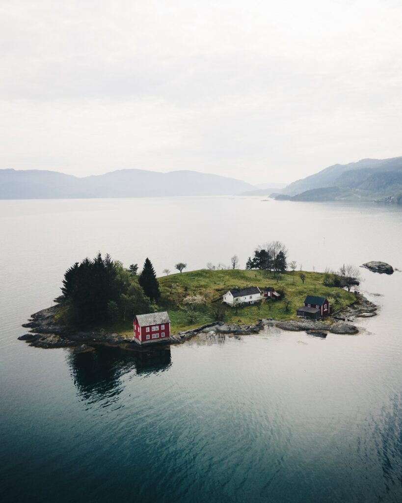 Aerial view of tranquil island with charming buildings lush greenery calm sea and distant mountains Wallpaper