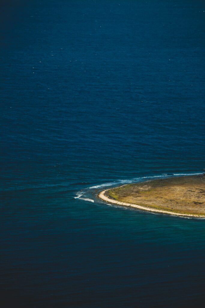Tranquil island coast with rugged shoreline and deep blue ocean minimalist wallpaper background