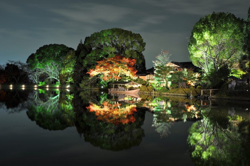 Serene Japanese coast evening with illuminated green red trees traditional house boat calm waters background Wallpaper