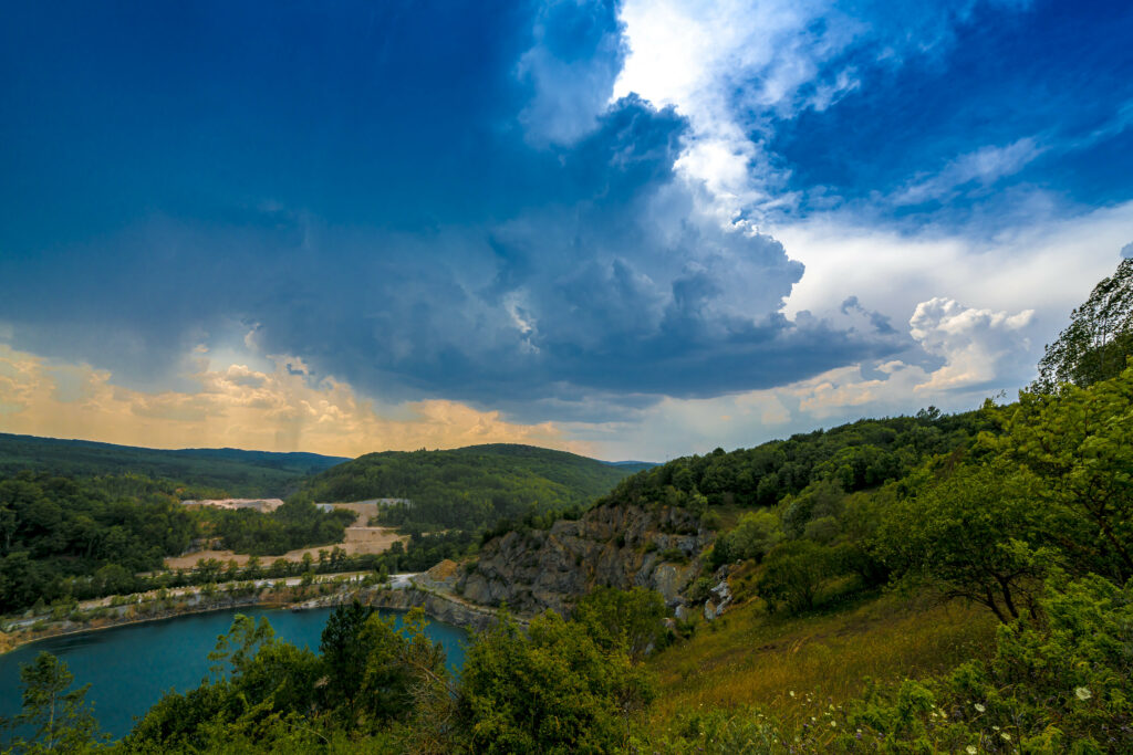 Vibrant landscape wallpaper with lush green trees shore tranquil lake dramatic clouds sky