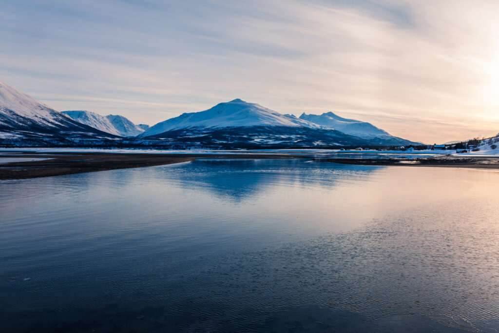 Tranquil lake reflecting snow-capped mountains under soft pastel sky serene winter landscape wallpaper