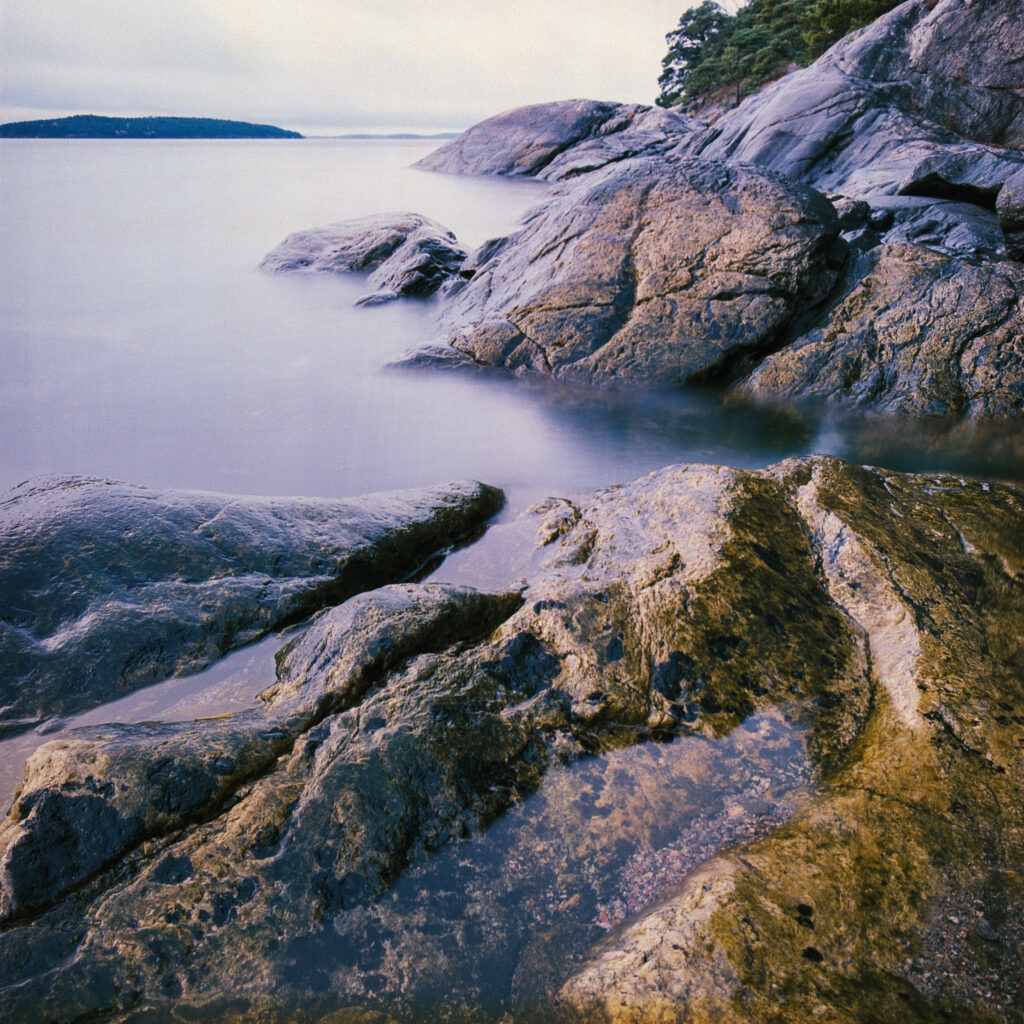 Serene lake wallpaper with reflective water rocky shore island and pastel sky for calm background