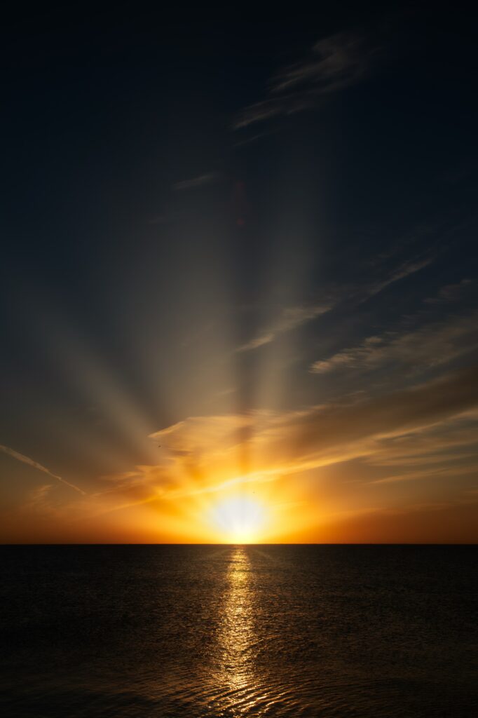 Tranquil lake at sunrise with golden light dramatic clouds warm orange and cool blue sky reflection Wallpaper