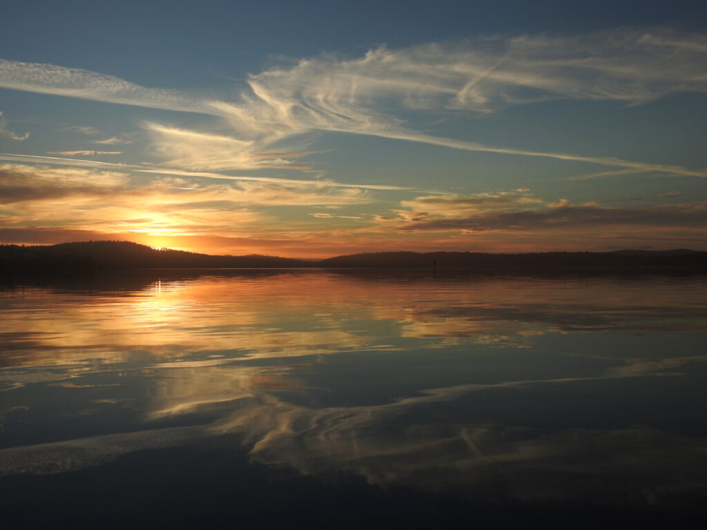 Serene sunset lake wallpaper with golden orange sky and glassy water reflection peaceful landscape