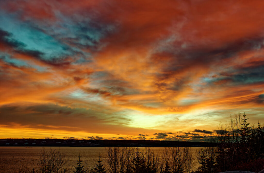 Sunset lake wallpaper with vibrant orange red blue sky and silhouetted trees at dusk