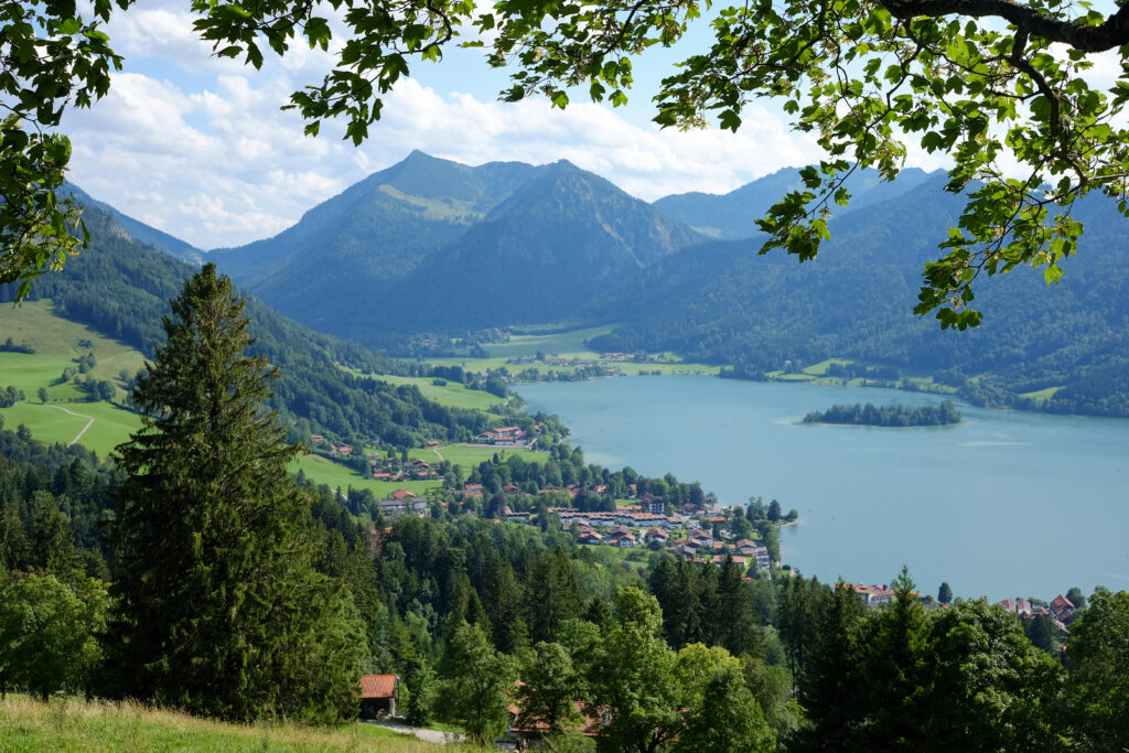 Aerial view of tranquil lakeside village with lush trees rolling mountains and scattered houses Wallpaper