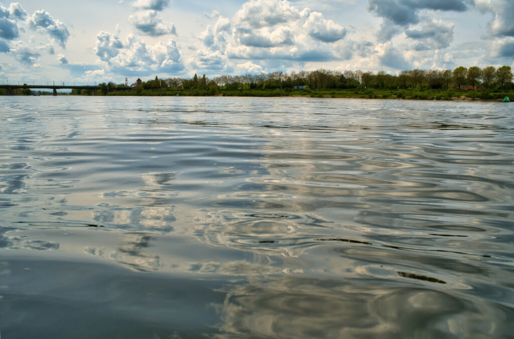 Tranquil lakeside wallpaper with reflective water lush trees and dramatic cloud sky background
