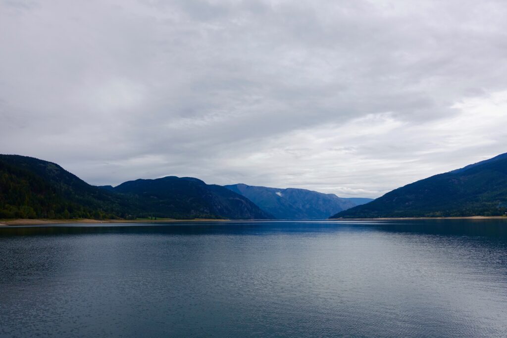 Serene lake reflection of blue green mountains under dramatic cloudy sky peaceful landscape wallpaper