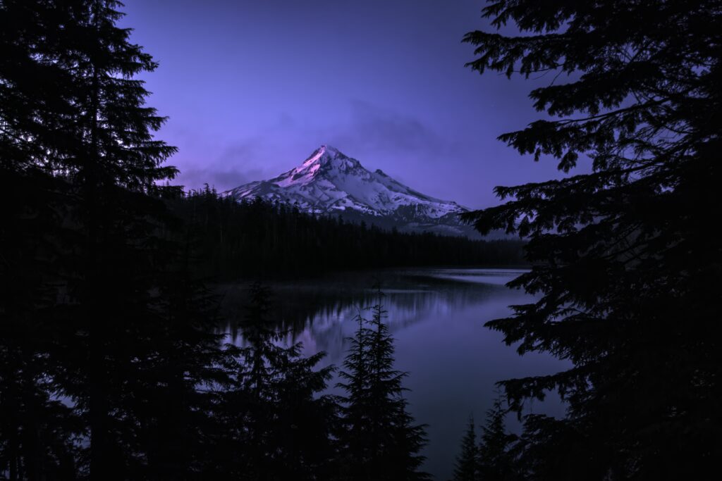Tranquil mountain landscape at twilight with snow-capped peak calm lake and tall evergreens wallpaper