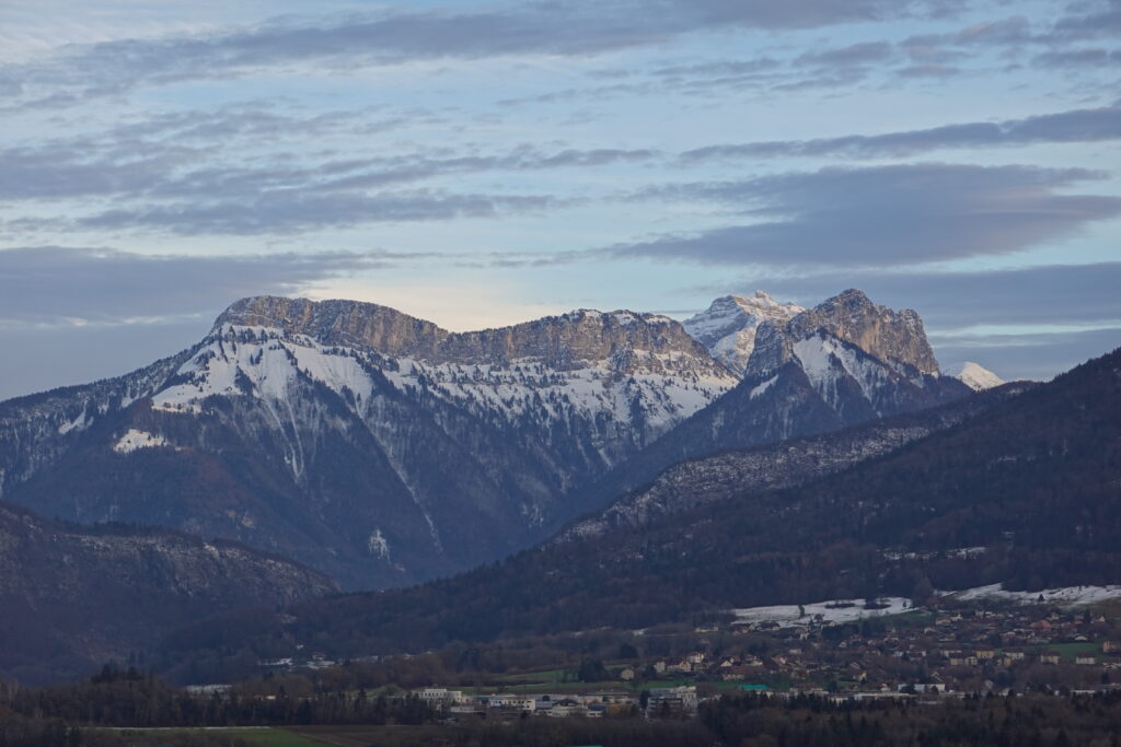 Breathtaking mountain landscape with snowy peaks lush trees and peaceful village in valley wallpaper