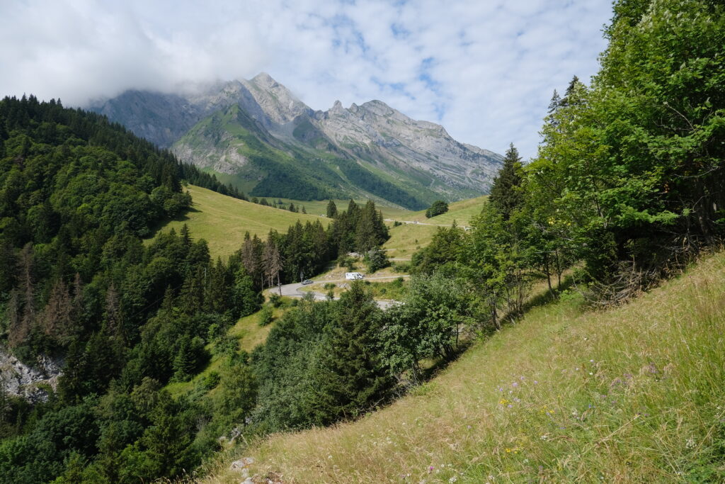 Stunning mountain landscape with lush green trees grassy slopes and dramatic cloud-covered peaks Wallpaper