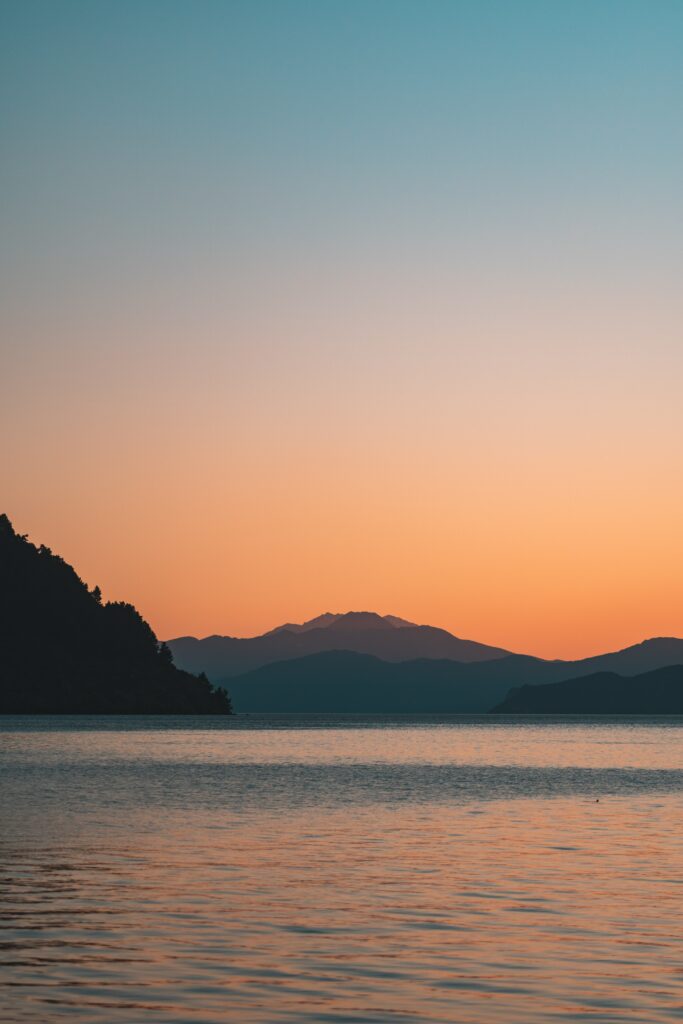 Tranquil mountain sunset with orange blue sky and water reflections peaceful nature wallpaper