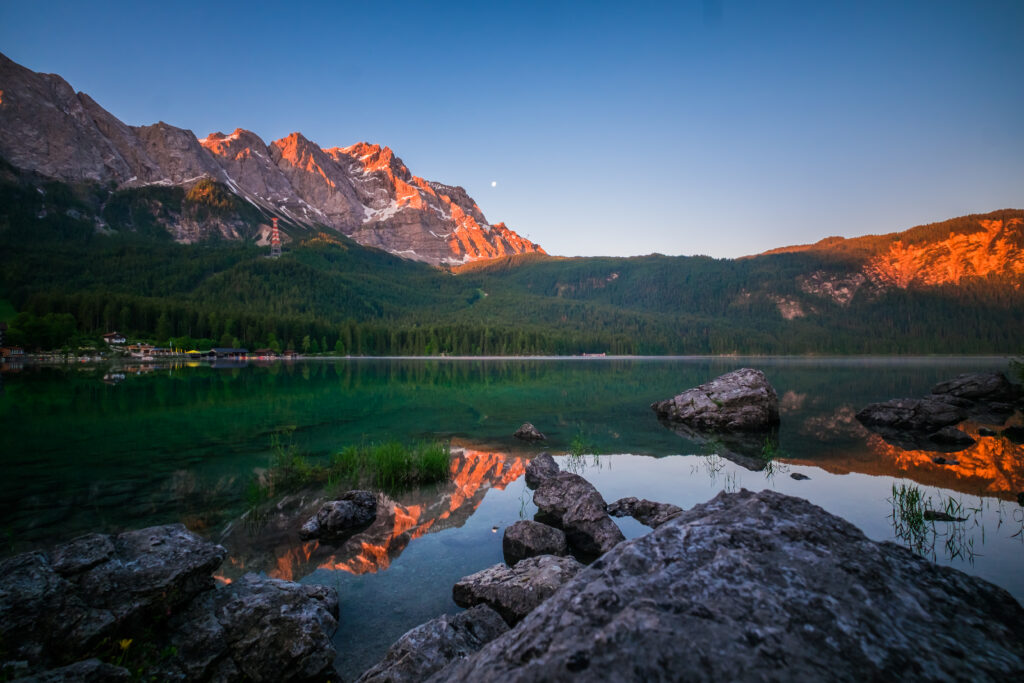 Sunset mountain landscape wallpaper with lake reflections forest and lakeside buildings background