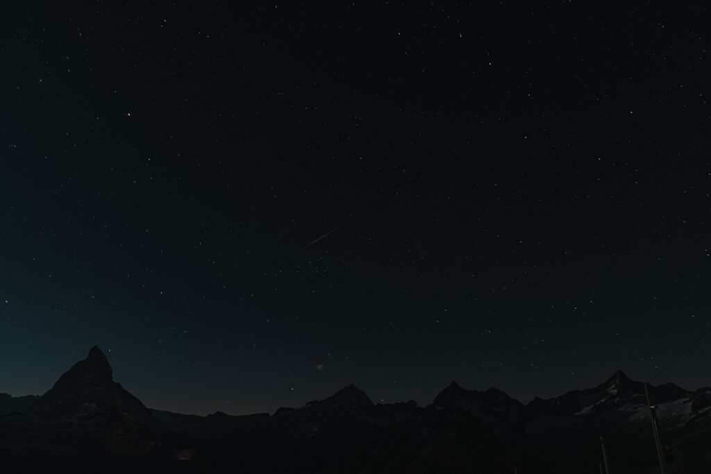 Majestic mountains and rugged rocks under a vast starry sky peaceful night scene wallpaper