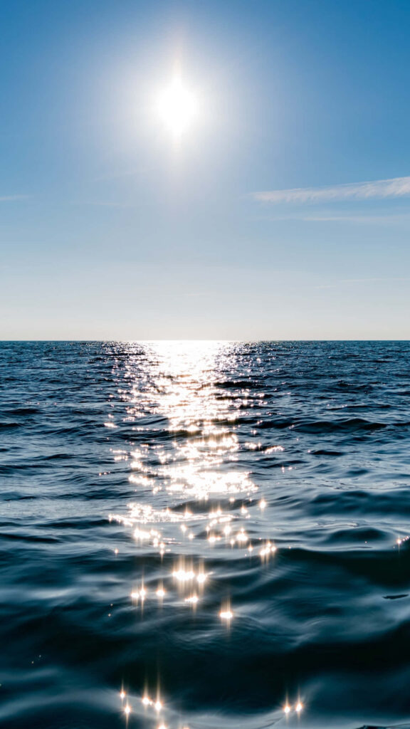 Tranquil Ocean Waves Wallpaper: Sunlight Reflections Under Clear Sky