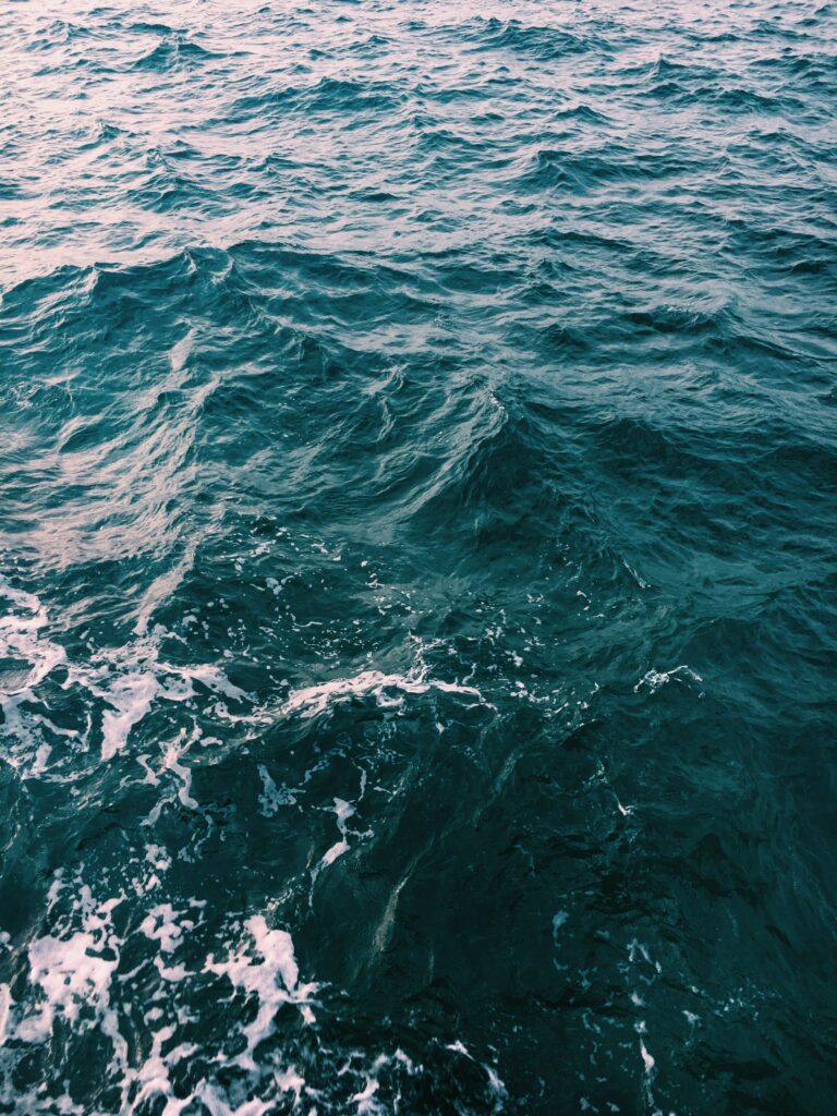 Dynamic ocean wallpaper with rolling waves deep teal turquoise water ripples and foam foam
