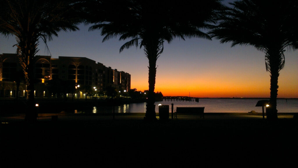 Serene Orange Sunset Wallpaper: Tranquil Waterfront Scene with Palm Trees