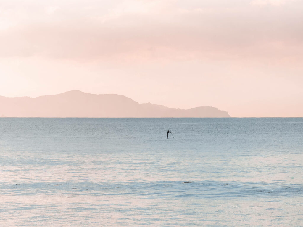 Tranquil Paddleboarder Wallpaper: Serene Pastel Blue Waters