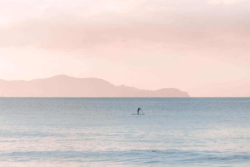 Tranquil Paddleboarder at Sunset: Serene Pastel Wallpaper Background