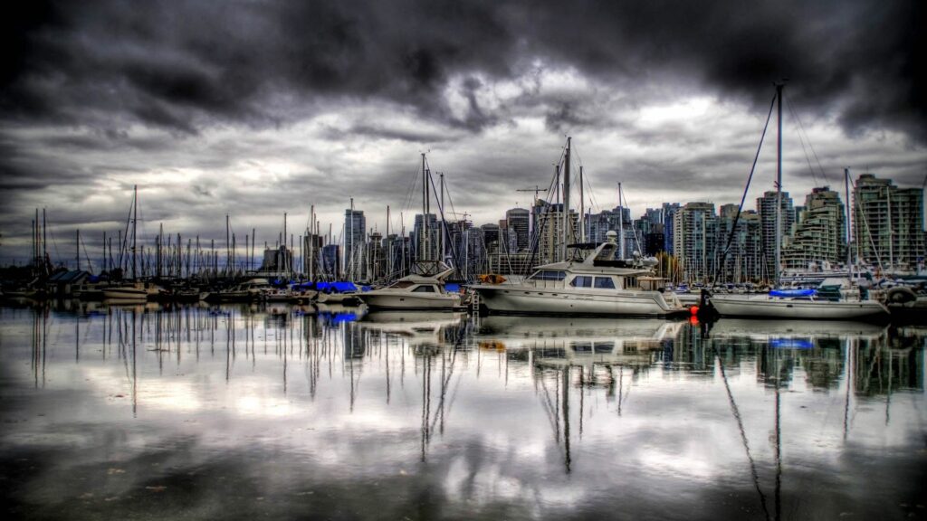 Serene Pier Wallpaper: Yachts by the Sea with Dramatic Cityscape