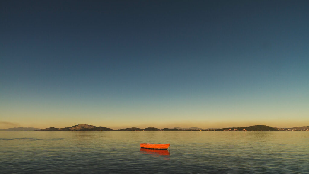 Red boat floating on calm Guanabara Bay Rio de Janeiro with mountains and clear sky background Wallpaper