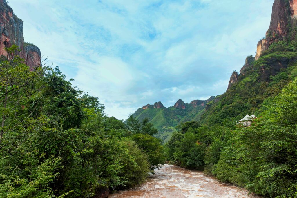 Tranquil river flowing through lush forest and mountains under clear bright blue sky landscape wallpaper
