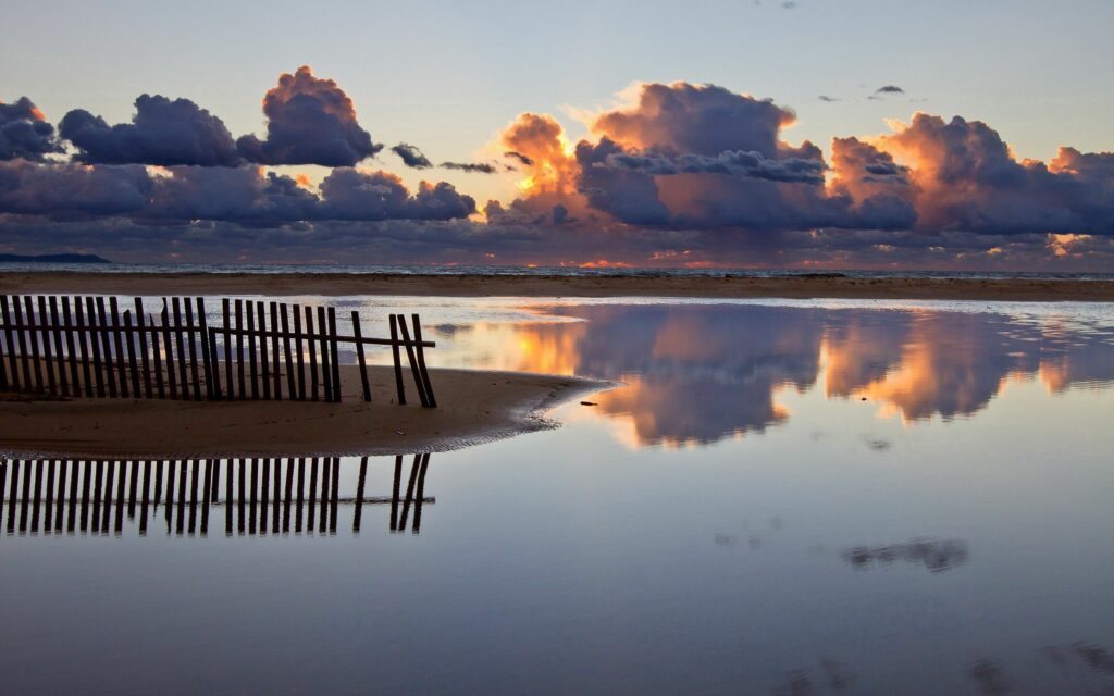 Tranquil river at sunrise with dramatic clouds calm water and rustic wooden fence landscape wallpaper