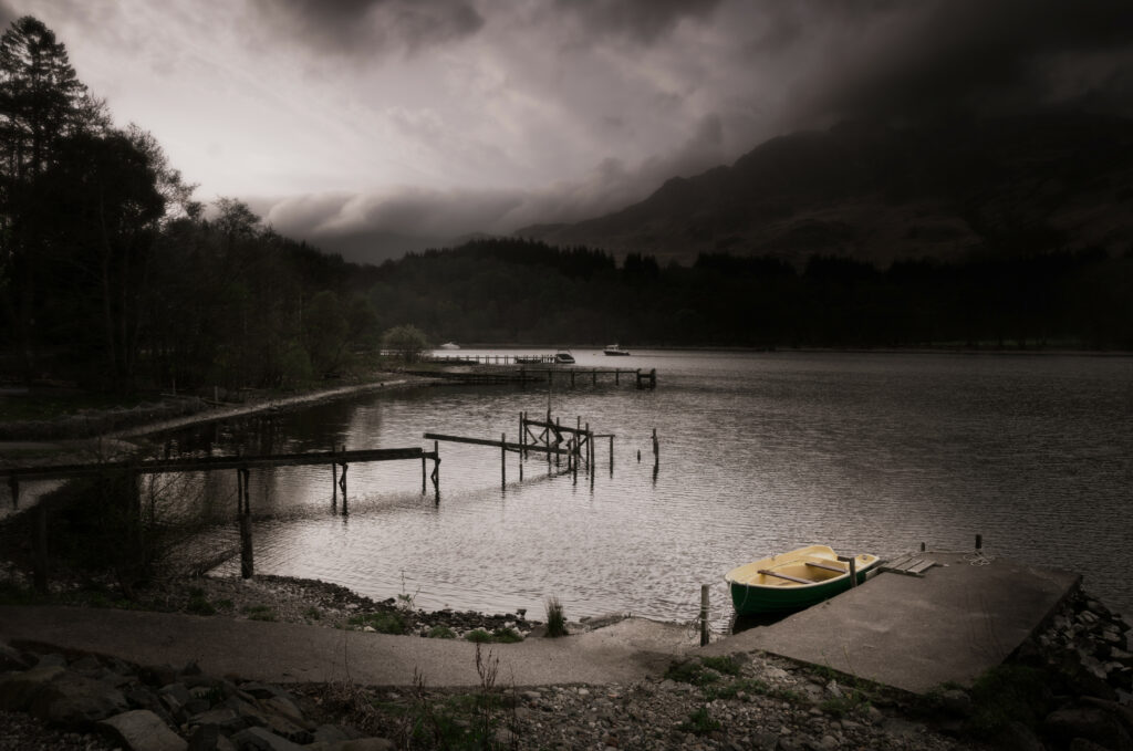 Yellow boat docked by weathered wooden pier with misty mountains and dense forest background Wallpaper