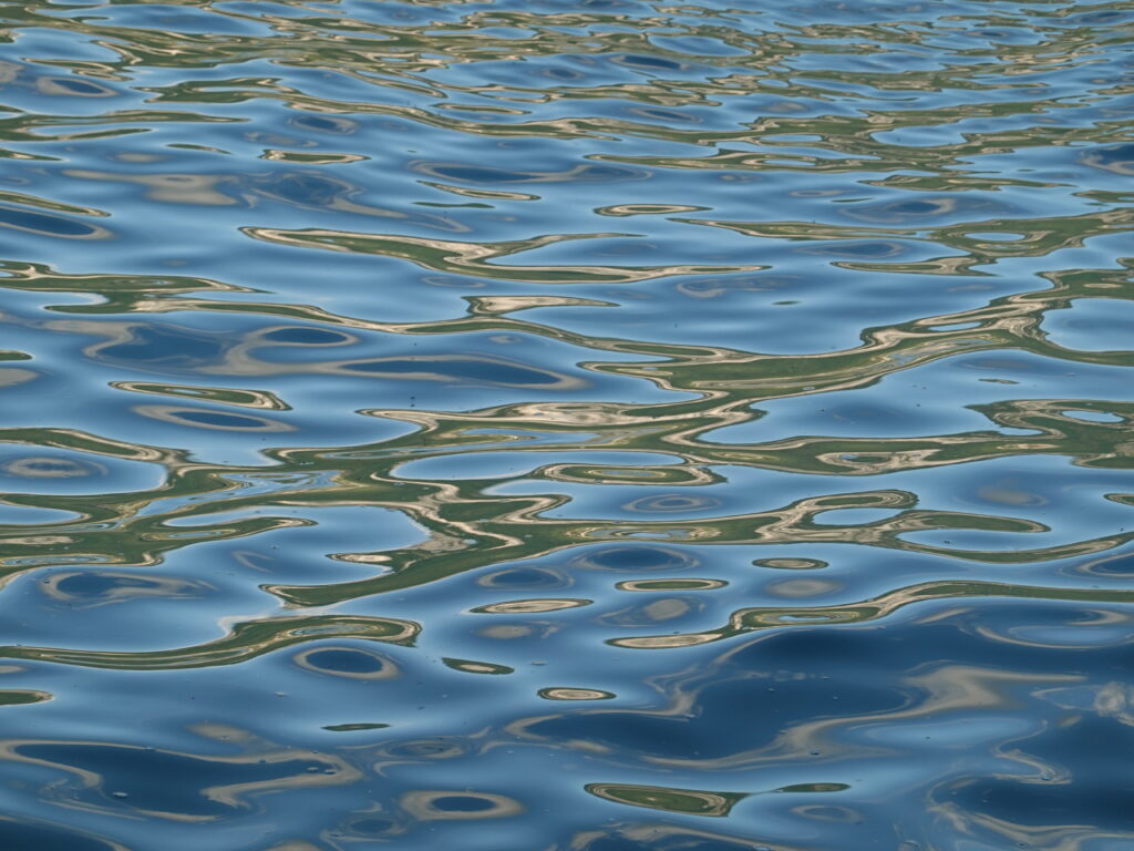 Tranquil sea surface with gentle waves and sunlight reflecting blue and silver tones wallpaper background