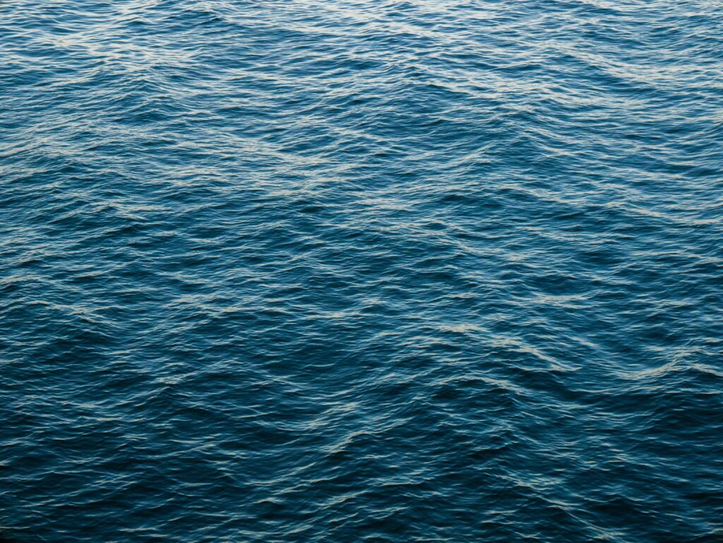 Tranquil sea wallpaper with gentle waves shimmering under sunlight on deep blue water surface
