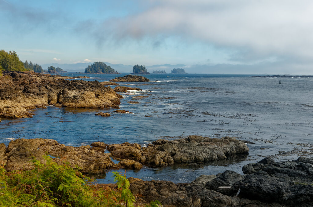 Tranquil seascape with rocky shores lush green islands calm blue waters under cloudy sky wallpaper