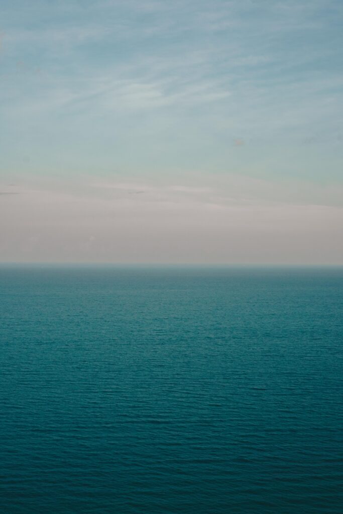 Tranquil seascape wallpaper with gentle ocean ripples under a soft blue sky horizon background