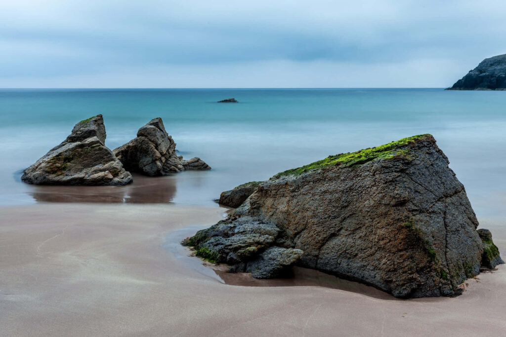 Tranquil Seaside Scene with Rock Formations and Calm Ocean Background Wallpaper