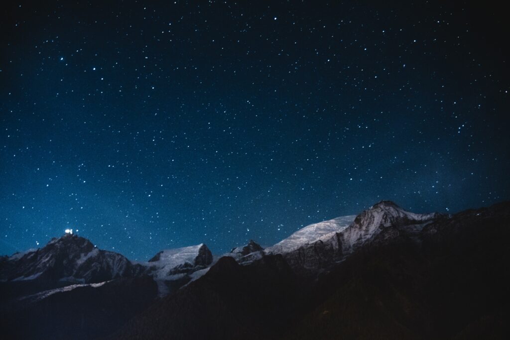 Starry night sky over snow-capped mountains serene wallpaper with deep blue hues and calm ambiance