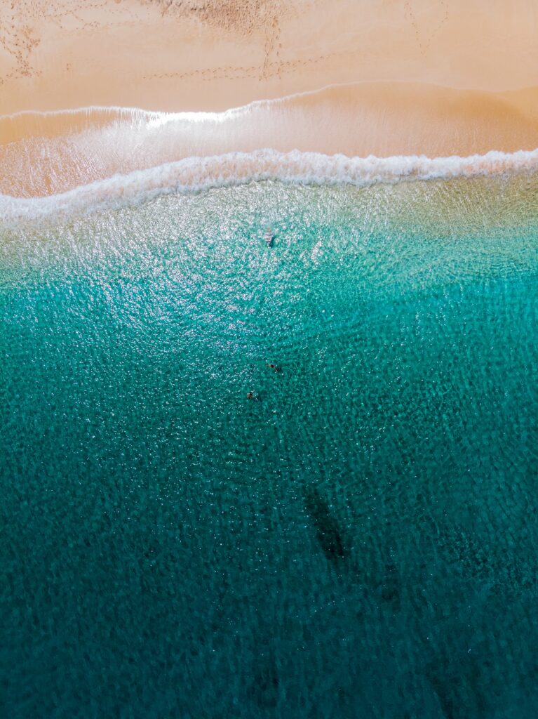 Aerial view of a tranquil summer beach with turquoise waters and golden sand under clear sky Wallpaper