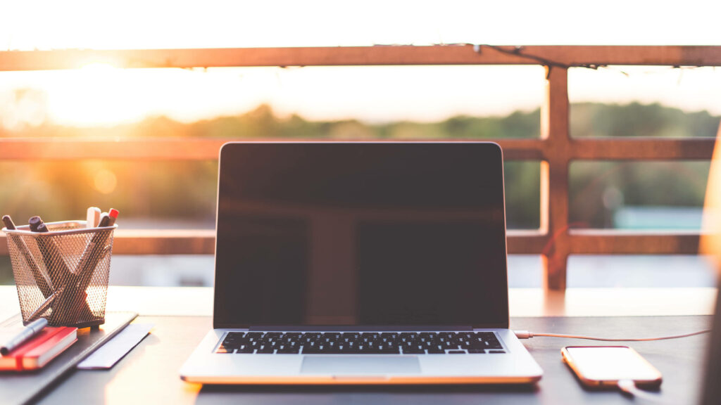 Serenity Captured: 4k Image Features a Laptop on an Outdoor Workspace with Tranquil Sunrise in Background Wallpaper