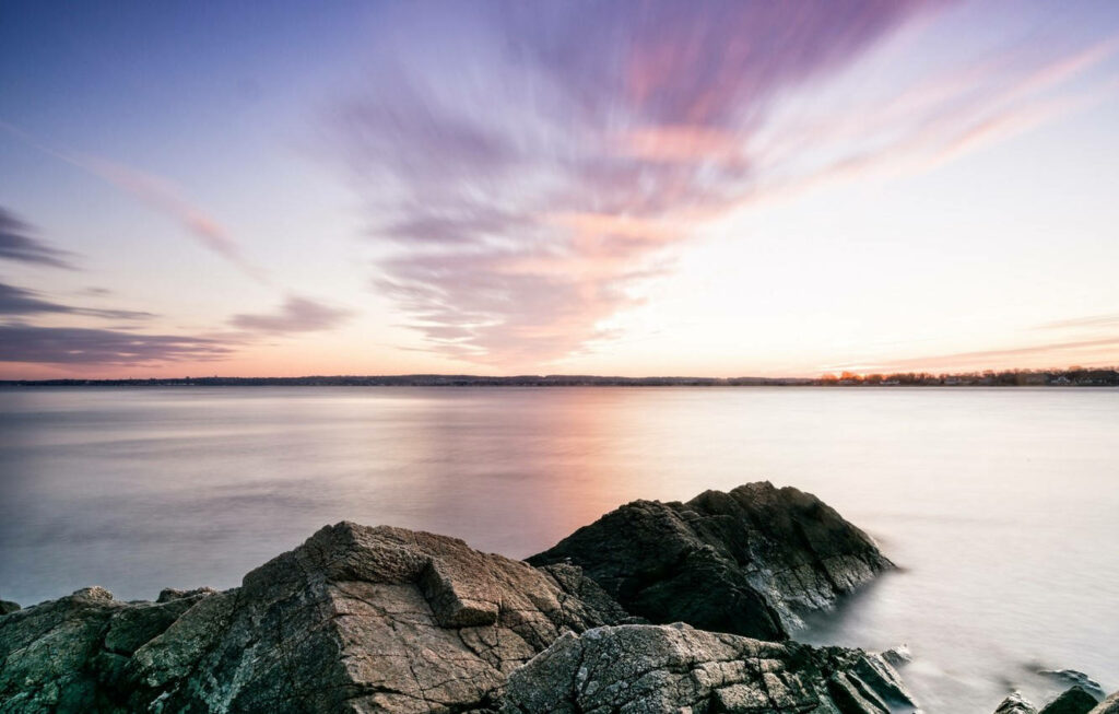 Tranquil Sunrise Beach Scene in Rhode Island: Calm Waters & Rocky Shore Wallpaper