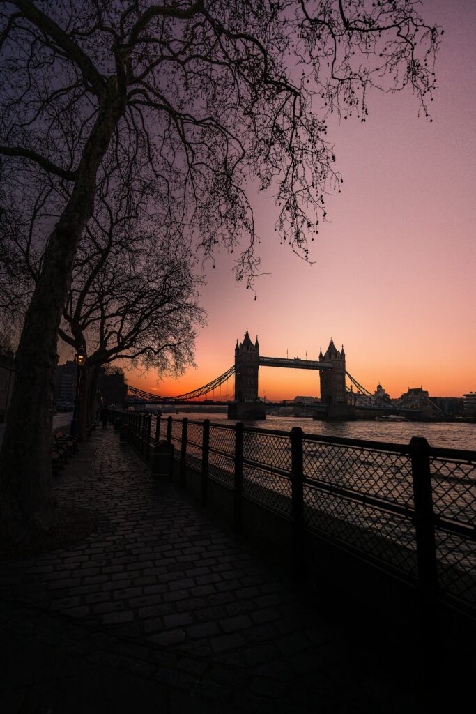 Tranquil Sunset Bridge Wallpaper Over Calm Water & Silhouetted Trees