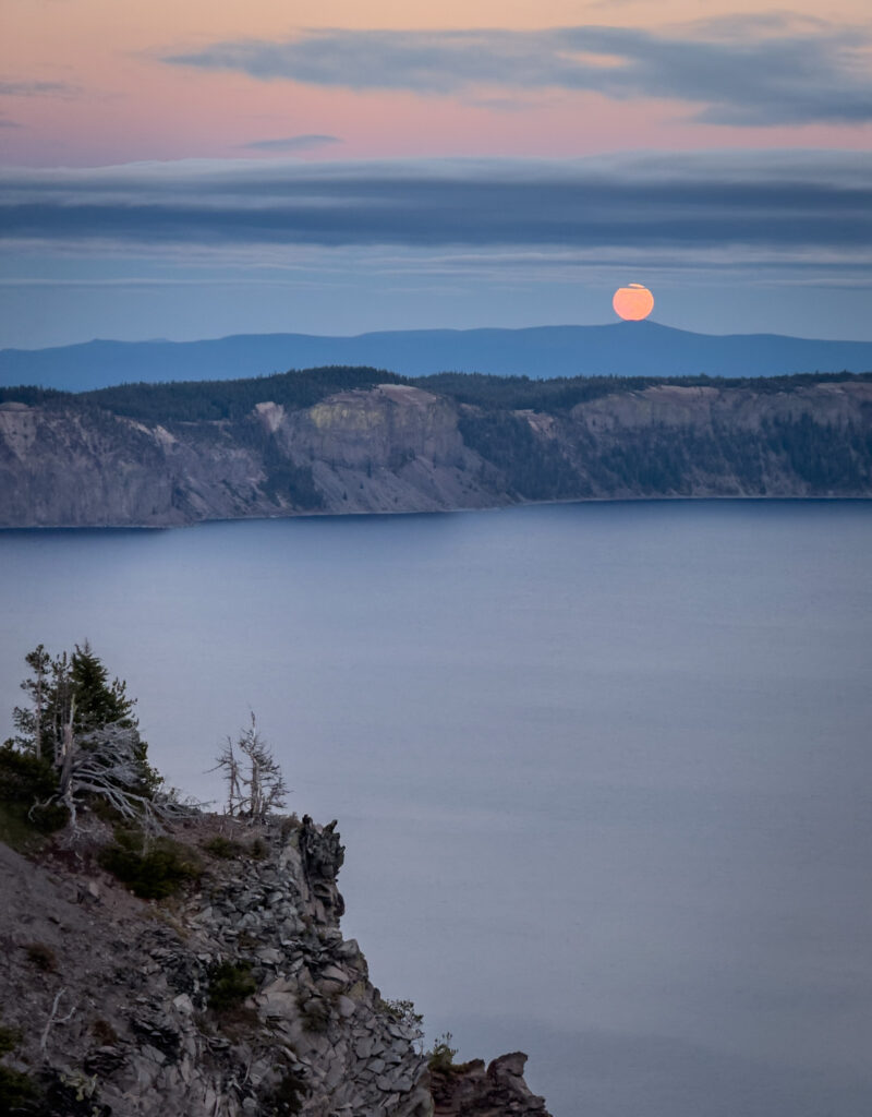 Serene lake sunset wallpaper with calm waters pastel sky tree-lined cliffs peaceful landscape