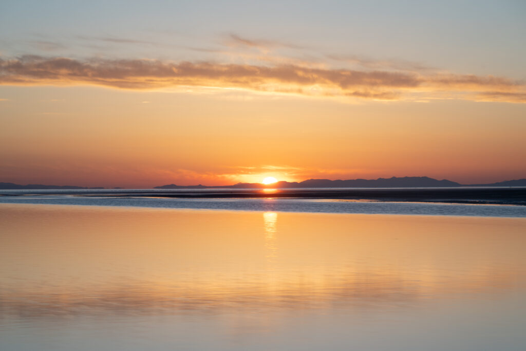 Sunset over tranquil lake with mountains reflection in warm orange and gold hues wallpaper
