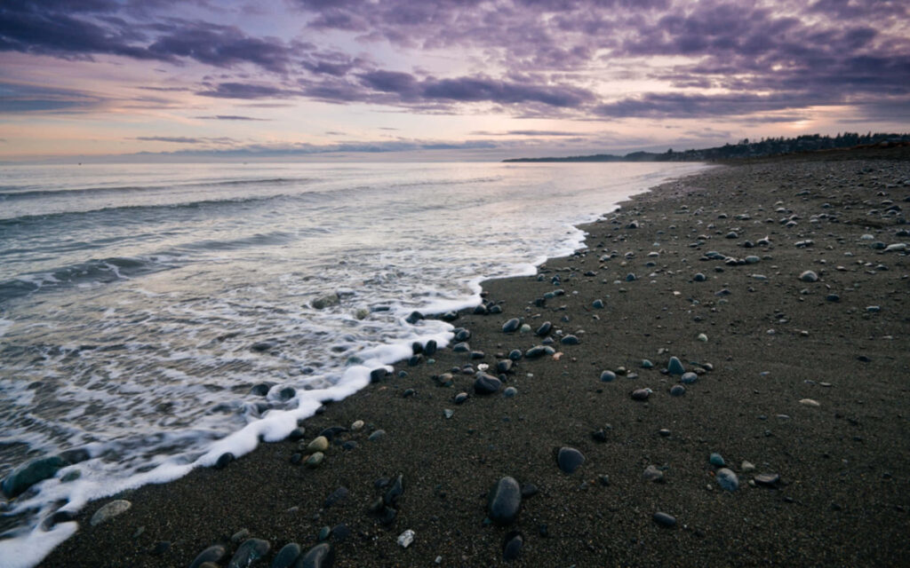 Tranquil Sunset Over Black Sand Beach - Vibrant Sky Background Wallpaper