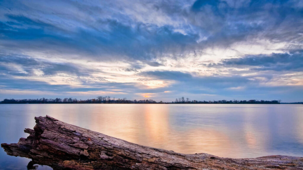 Tranquil Sunset Reflections on a Serene Lake Amidst Majestic Trees Wallpaper