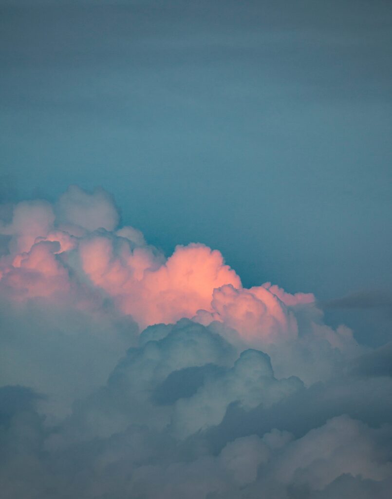 Soft clouds drift in pastel pink and blue sunset sky serene calm wallpaper background scene