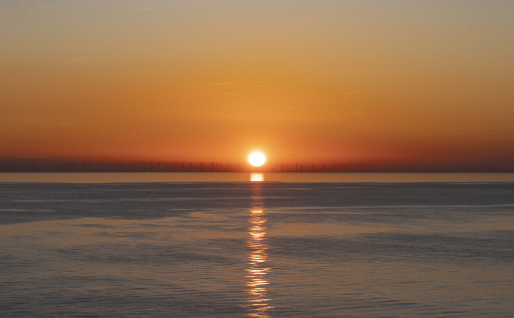 Vibrant orange sunset over calm sea with golden reflections and serene dusk sky wallpaper background